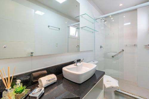 Baño blanco con lavabo y espejo en Campos de Canela 402 - Stay House Temporada, en Canela