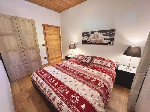 um quarto com uma cama com uma colcha vermelha e branca em Chalet Bel-Air A due passi dalle piste, con giardino e posto auto em Temù