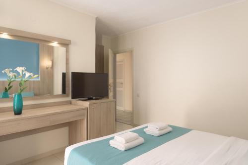 een slaapkamer met een bed en een flatscreen-tv bij Central Hersonissos Hotel in Chersonissos