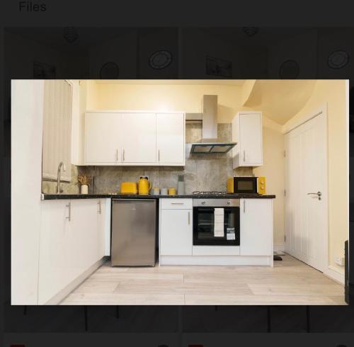 a kitchen with white cabinets and a stove top oven at St James House - Sleeps 8! in Leeds