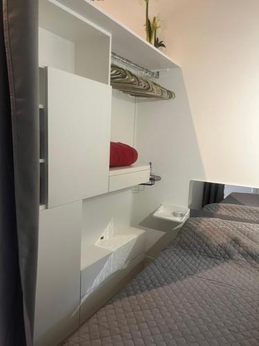 um quarto branco com uma cama e uma almofada vermelha em Mimosas Cottage 2 Pièces eze bord de mer em Èze