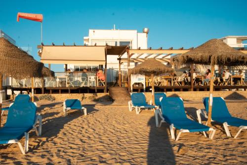 a group of chairs and umbrellas on a beach at Wax Suite By the sea in Faro