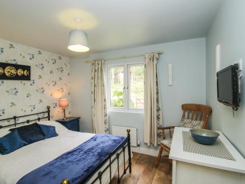a bedroom with a bed and a tv and a chair at Dragonfly Lodge in Shrewsbury