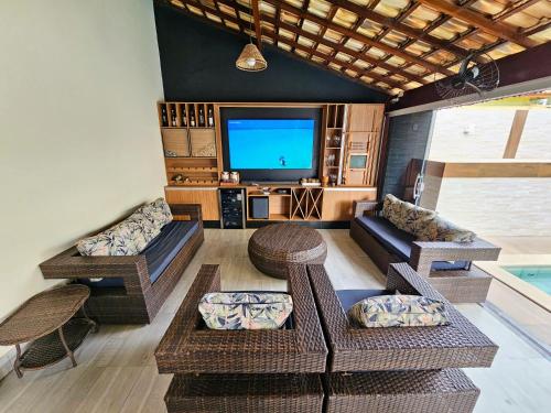 sala de estar con muebles de mimbre y TV de pantalla plana. en Casa em Grussai 6 quartos e piscina Sâo Joâo da Barrra-RJ, en São João da Barra