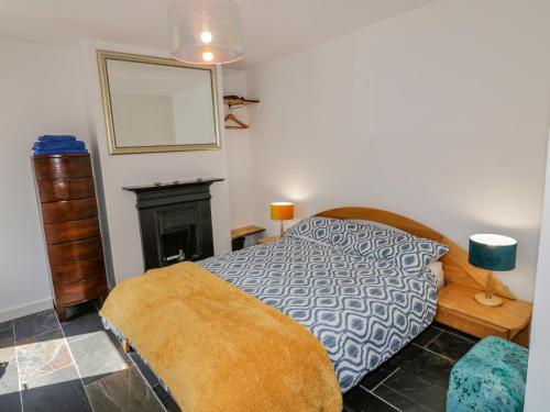 1 dormitorio con 1 cama y chimenea en Gun Powder Cottage, en Tighnabruaich