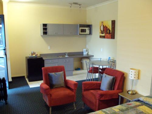 ein Wohnzimmer mit einer Küche, 2 Stühlen und einem Tisch in der Unterkunft At The Rocks Motorlodge in Napier