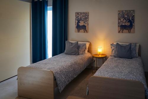 duas camas num quarto com cortinas azuis e uma janela em Comfort and Convenience flat 4 dad's court em St. Paul's Bay