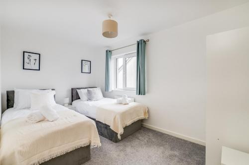 1 dormitorio con 2 camas y ventana en 3 bedroom detached house free car park close to town airport en Luton