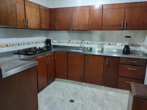 a kitchen with wooden cabinets and a stainless steel sink at Casa, Apartamento en Buga (Valle) in San Juanito