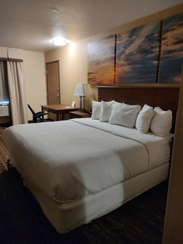 Habitación de hotel con cama grande con almohadas blancas en Days Inn & Suites by Wyndham Fargo 19th Ave/Airport Dome, en Fargo