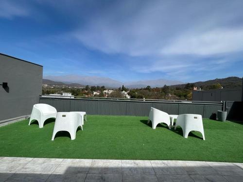 a group of white chairs sitting on top of grass at Apartamentos El Fortín in San Salvador de Jujuy