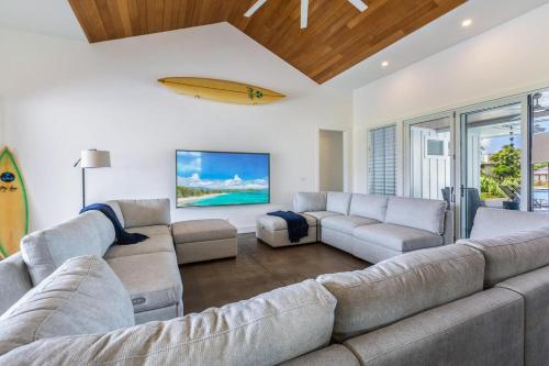 een woonkamer met een grote bank en een surfplank aan de muur bij Kauai Tradewinds home in Princeville