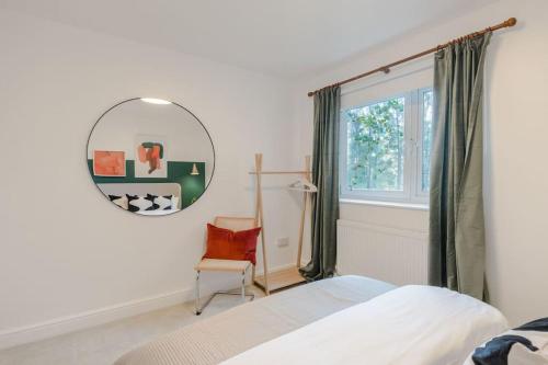 1 dormitorio con cama, espejo y silla en The Clissold, Two Bedroom Apartment N5, en Londres