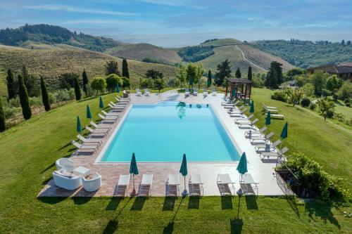 einen Blick über einen Pool auf einem grünen Feld mit Stühlen in der Unterkunft Agriturismo Pelagaccio in Peccioli