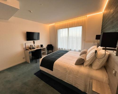 a bedroom with a bed with a desk and a window at LE MANOIR DU ROSELIER HOTEL 3 étoiles in Plérin