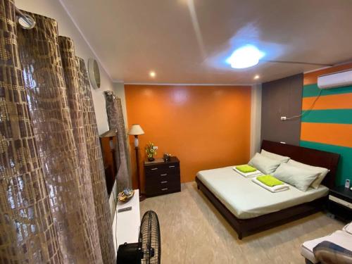 Dormitorio pequeño con cama y pared de color naranja en Peach Haven, en Cebú