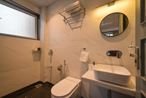 a bathroom with a toilet and a sink and a mirror at Elegant Villa By Tropicana Stays in Lonavala