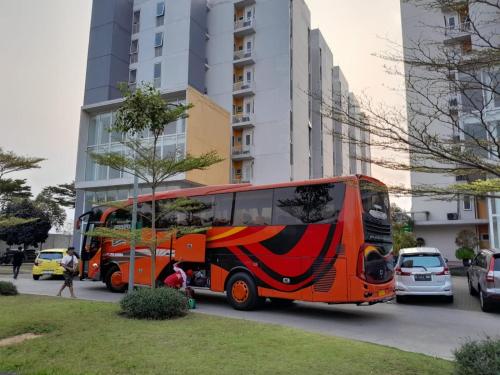 um autocarro laranja está estacionado num parque de estacionamento em NATURE INN Aeropolis AR3 em Tangerang