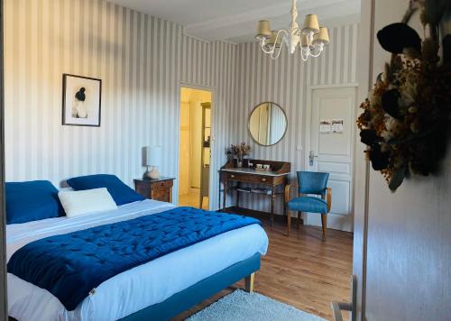 a bedroom with a blue bed and a desk and a mirror at Au fil de L'Ouanne 