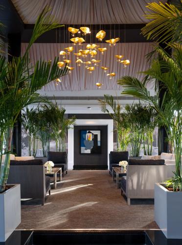a lobby with couches and palm trees and a chandelier at Raffles Al Areen Palace Bahrain in Manama