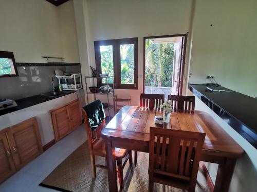a kitchen with a wooden table and chairs in a kitchen at Links Sunset Beach House in Amphoe Koksamui