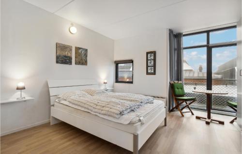 ein weißes Schlafzimmer mit einem Bett und einem großen Fenster in der Unterkunft Fan Bad, Lejl, 50 in Fanø