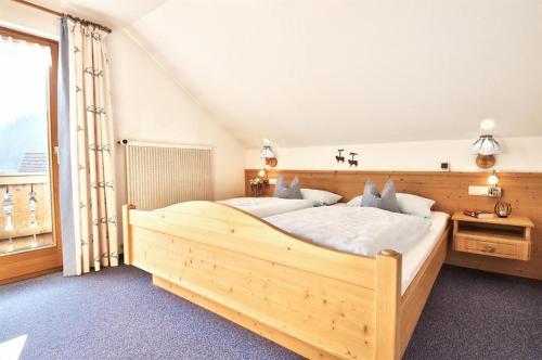 a large wooden bed in a room with a window at Haus Kaufmann in Bad Hindelang