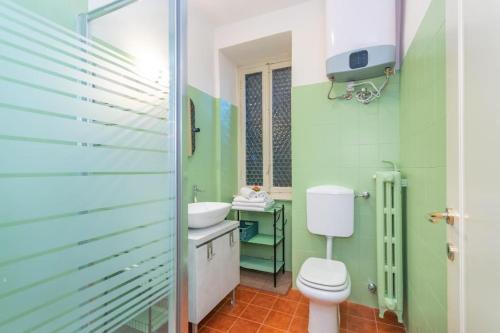 a green bathroom with a toilet and a sink at Liberty Suite in Turin
