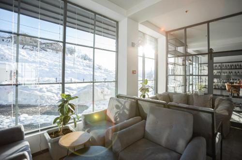 a living room with a couch and a large window at Hotel Roshe Gudauri in Gudauri