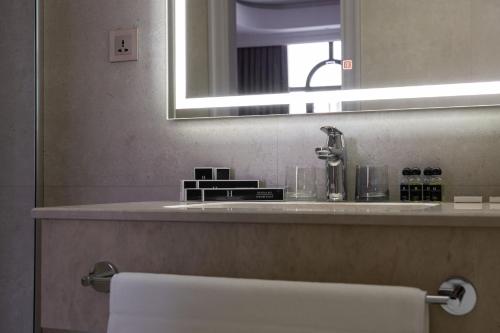 La salle de bains est pourvue d'un lavabo et d'un miroir. dans l'établissement FrankFort Expo Hotel, à Tachkent