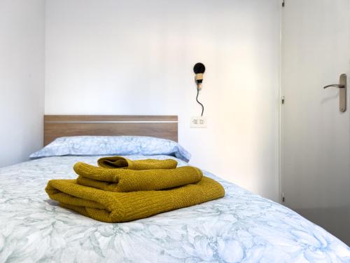 a yellow blanket sitting on top of a bed at Luminoso Apartamento a 4 min del Museo Dalí - Caserna 13 in Figueres
