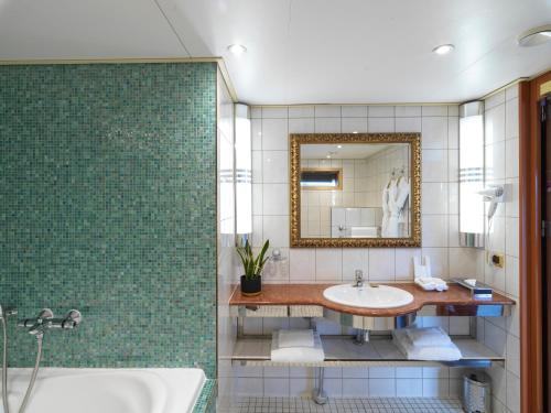a bathroom with a sink and a mirror and a tub at Sunborn London Yacht Hotel in London