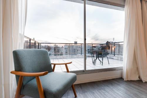 a living room with a chair and a balcony at Punta Trouville Hotel in Montevideo