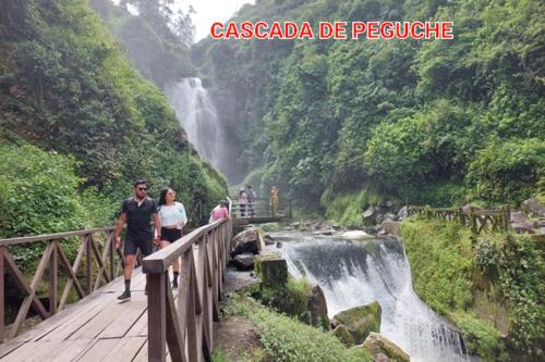 a group of people walking on a bridge over a waterfall at Casa Apartamento Campestre en las Faldas del Tayta Imbabura in San Juan de Ilumán