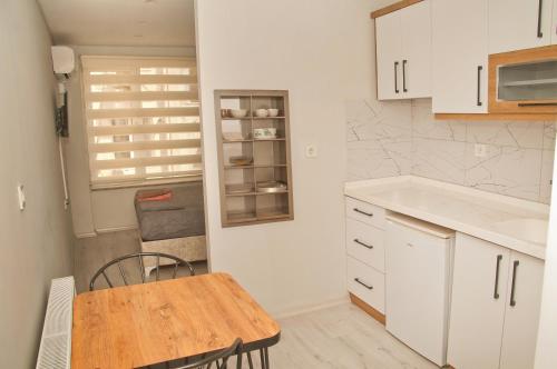 cocina con armarios blancos y mesa de madera en Balıkesir Suit, en Balıkesir