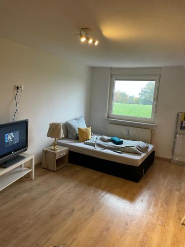 a bedroom with a bed and a tv and a window at Stadtrand Oase Appartement in Spenge