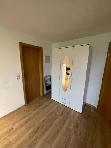 an empty room with a white cabinet with a mirror at Stadtrand Oase Appartement in Spenge