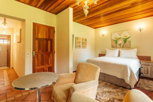 een slaapkamer met een bed en een tafel en stoelen bij Pousada Serra Villena in Monte Verde