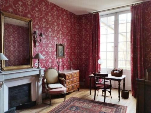 a living room with a fireplace and red wallpaper at Barabans Tower Cluny Abbay in Cluny