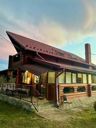a house with a porch and a chair in front of it at Садиба Карпат in Verkhovyna