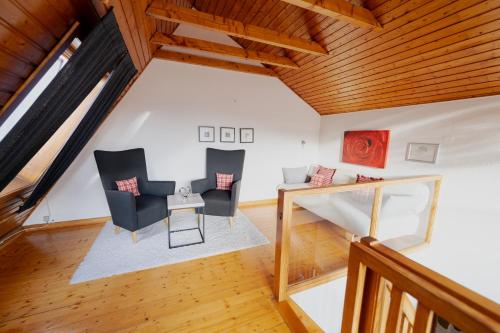 an attic room with two chairs and a table at Ferienhaus Schöne Aussicht Ferienwohnung Rot in Hemfurth-Edersee
