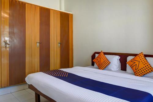 een slaapkamer met een bed met oranje en blauwe kussens bij SPOT ON Anjana Home Stay in Dehradun