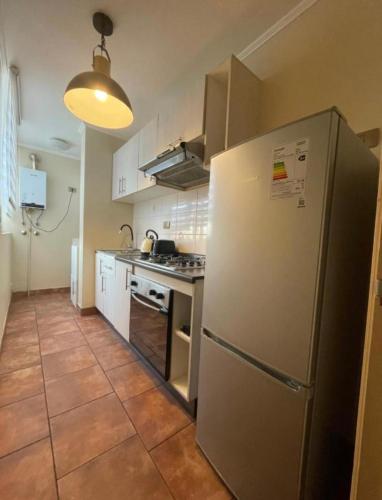 una cucina con frigorifero in acciaio inossidabile e armadietti bianchi di Depto para 2 a 4 personas a Curicó