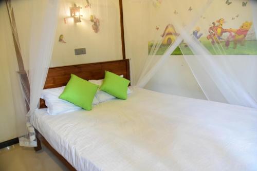 a bedroom with a bed with two green pillows at Sanjee Villa Hikkaduwa in Hikkaduwa