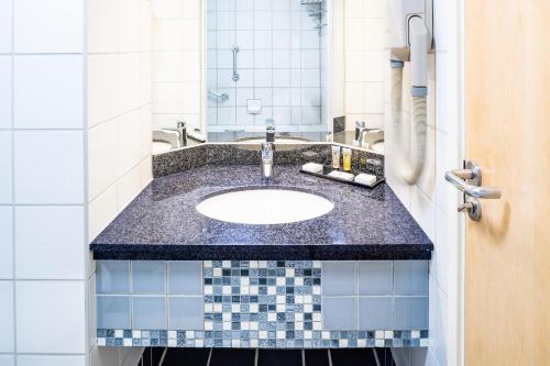 een badkamer met een wastafel en een spiegel bij Copthorne Hotel Slough Windsor in Slough