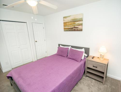 a bedroom with a purple bed and a ceiling fan at Cresent Beach House by Palmetto Vacation Rentals in Myrtle Beach