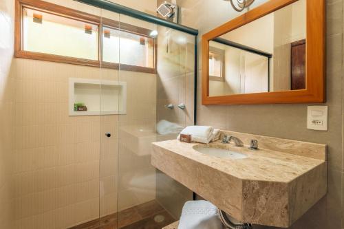 a bathroom with a sink and a mirror and a shower at Pousada Serra Villena in Monte Verde