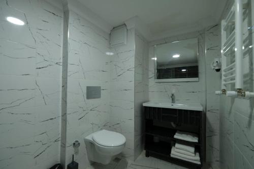 La salle de bains blanche est pourvue de toilettes et d'un lavabo. dans l'établissement Cevvo Hotel, à Istanbul