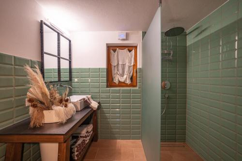 uma casa de banho com azulejos verdes, um lavatório e um espelho. em Chalet Frederik em Fontanella