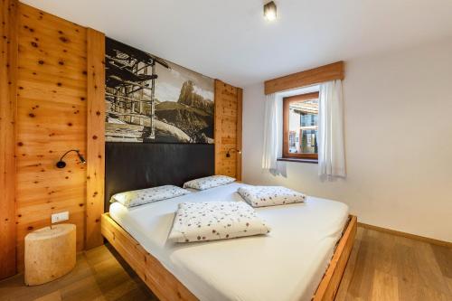 1 dormitorio con 1 cama grande con sábanas y almohadas blancas en Naturoase Stegerhof Apt Iris, en Trodena